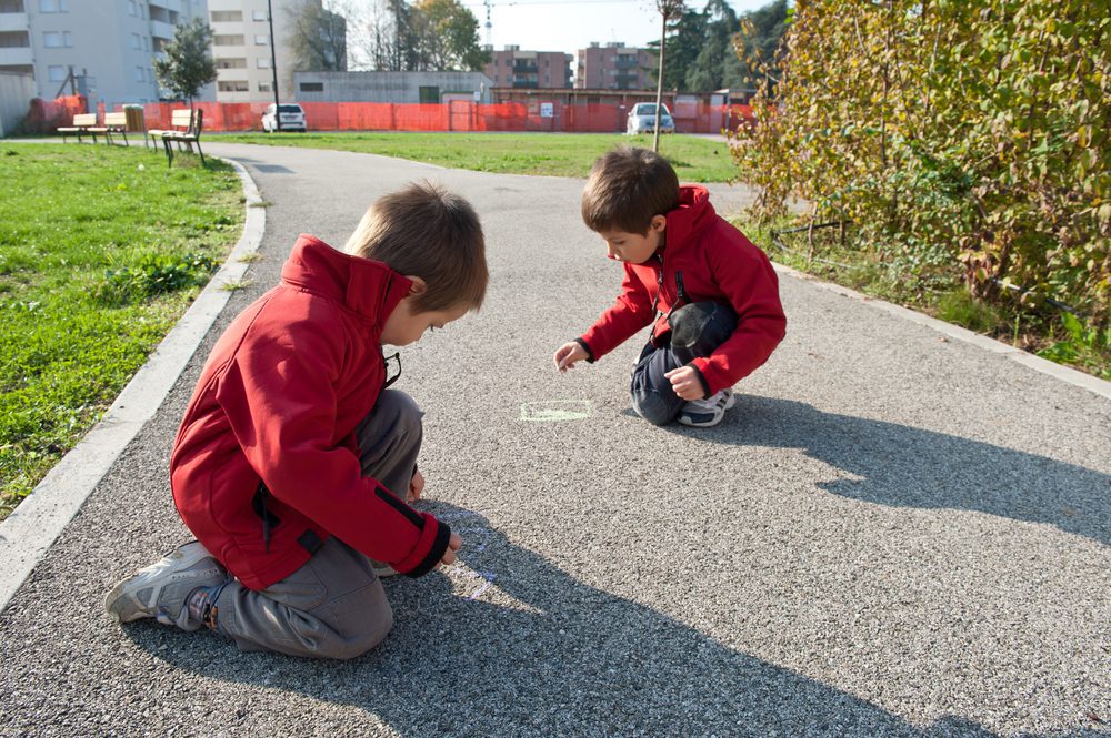 Children drawing with chalk on park pathway
