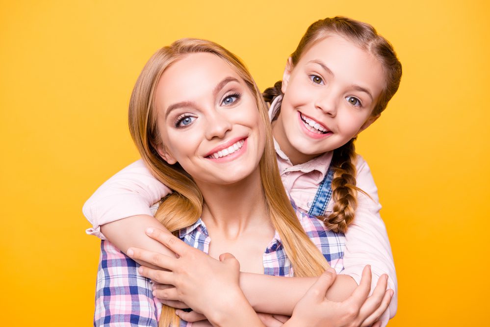 Smiling woman and girl with yellow background
